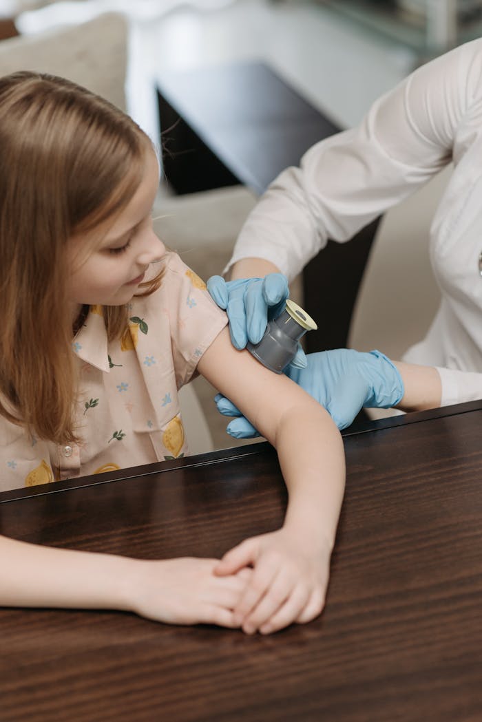 Child undergoing a blood sugar level test during a medical consultation indoors.